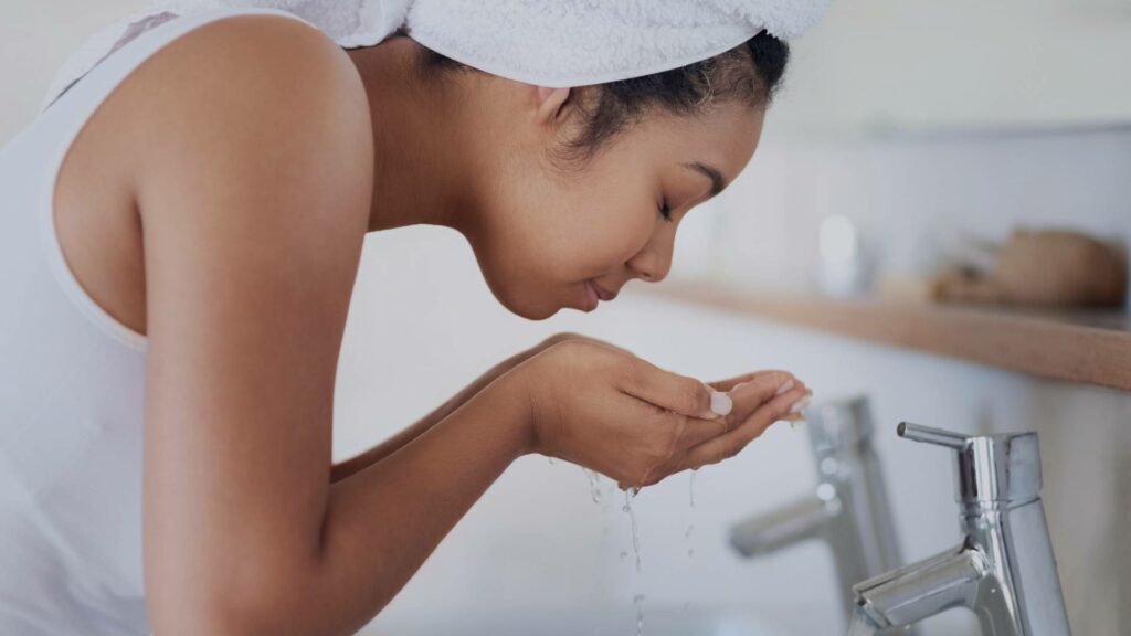 Femme qui se passe de l'eau sur le visage