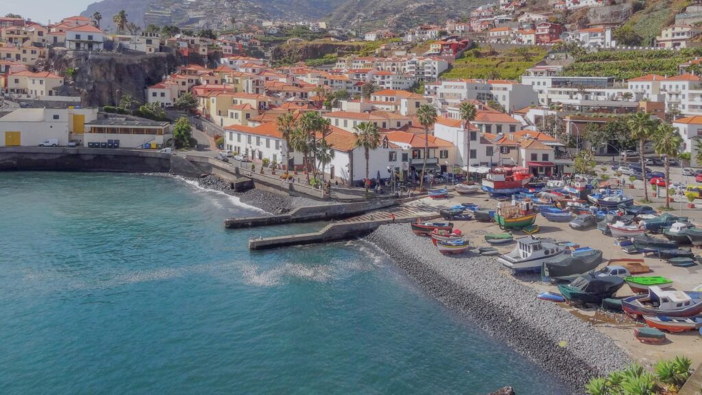 Vue panoramique sur Funchal avec l'océan Atlantique en arrière-plan, jardins luxuriants et maisons colorées.