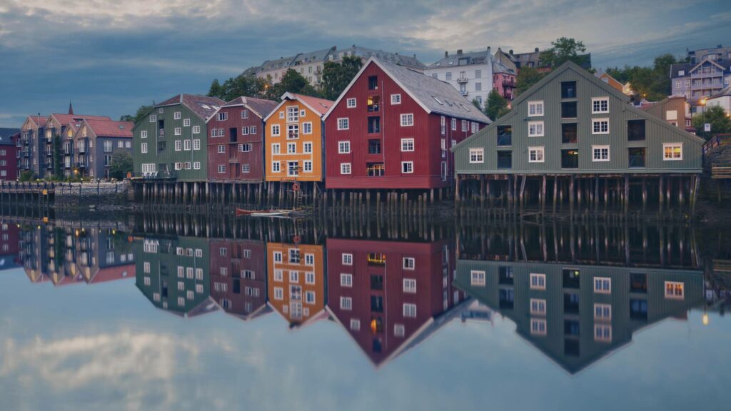 Vue panoramique de Trondheim avec ses maisons colorées bordant le fleuve, offrant un paysage pittoresque et charmant.