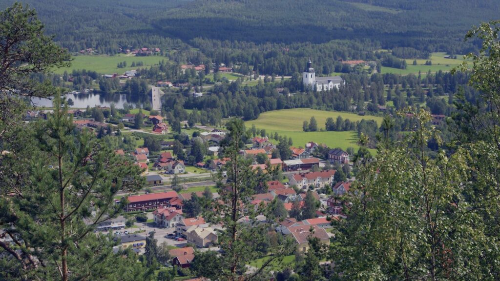 Vue aérienne du village de Hälsingland depuis les hauteurs, avec des maisons traditionnelles entourées de verdure.