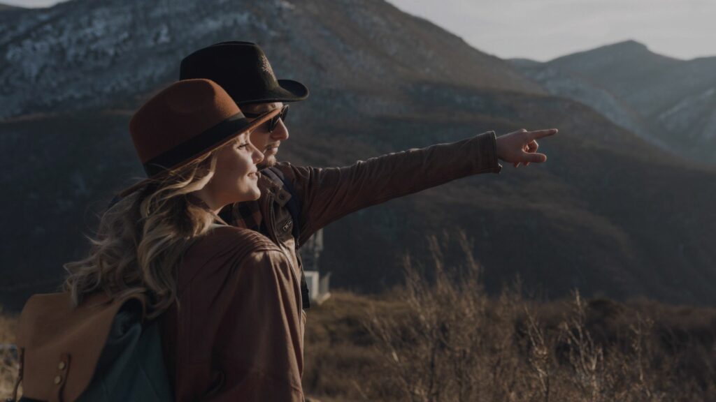 Voyageurs sur un sentier de montagne, regardant l’horizon, symbolisant l’aventure intérieure et la croissance personnelle.