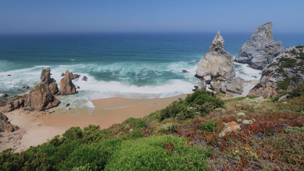 Vue panoramique de Praia da Ursa, plage sauvage avec formations rocheuses imposantes et eaux cristallines, Portugal