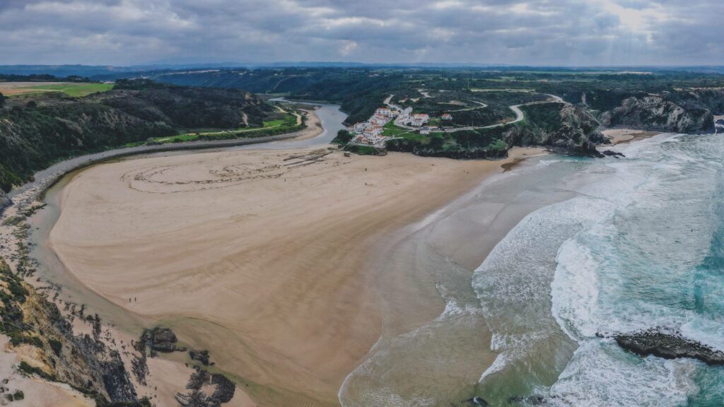 Praia de Odeceixe, plage unique avec rivière et océan se rejoignant, encadrée par un village pittoresque