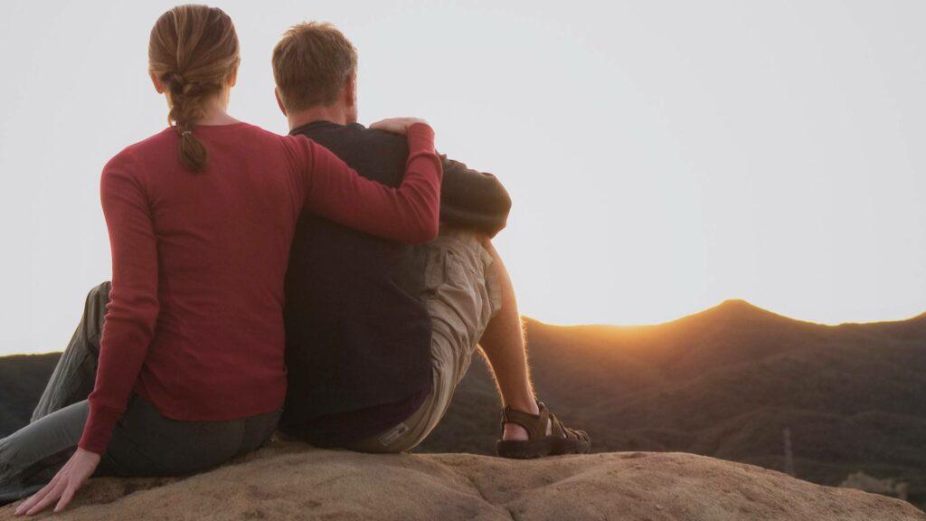 Couple regardant un coucher de soleil sur la côte portugaise, moment de contemplation et de saudade