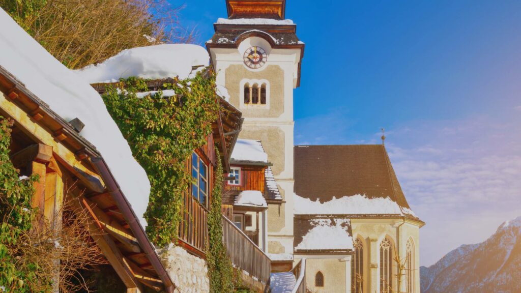 Place principale de Hallstatt en hiver, avec son église baroque et ses maisons colorées couvertes de neige.