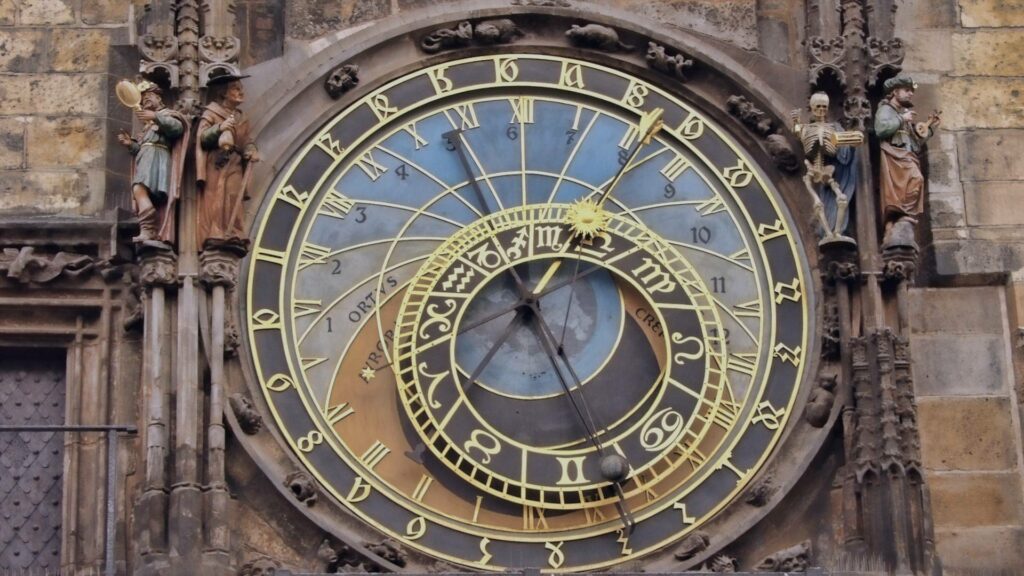 Horloge astronomique ornée de détails gothiques recouverte de neige.