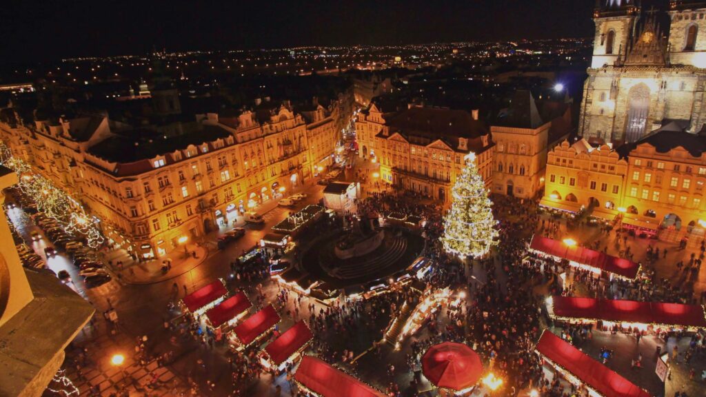 Chalets en bois illuminés au marché de Noël de Prague avec un grand sapin décoré.