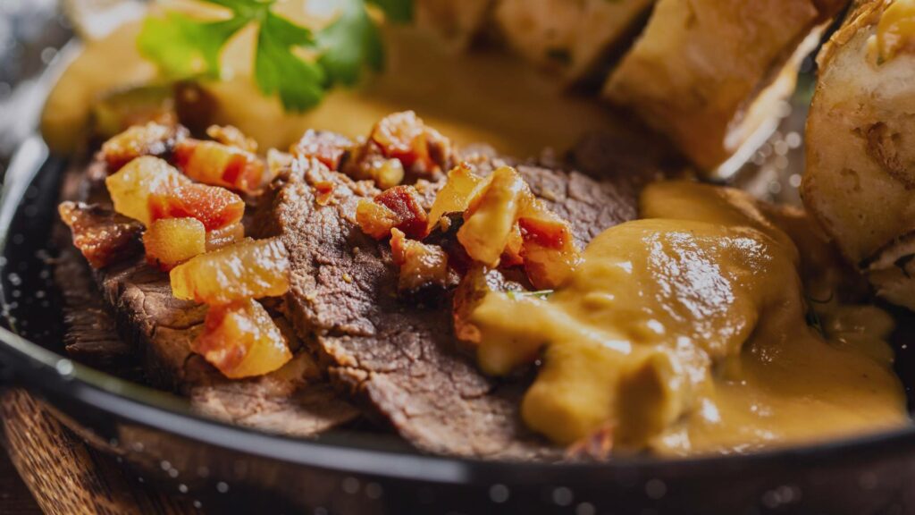 Assiette de Svíčková avec boulettes de pain, sauce crémeuse et airelles.