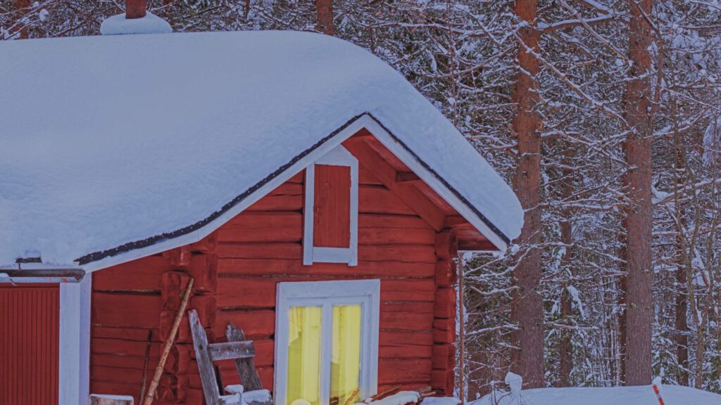 Petite maison rouge entourée de neige au cœur de la forêt du Hälsingland, un paysage emblématique du roman Là où nous avons existé de Lina Nordquist.